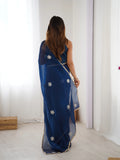 Woman wearing a blue saree with white floral patterns in a minimal indoor setting Glanzavi.
