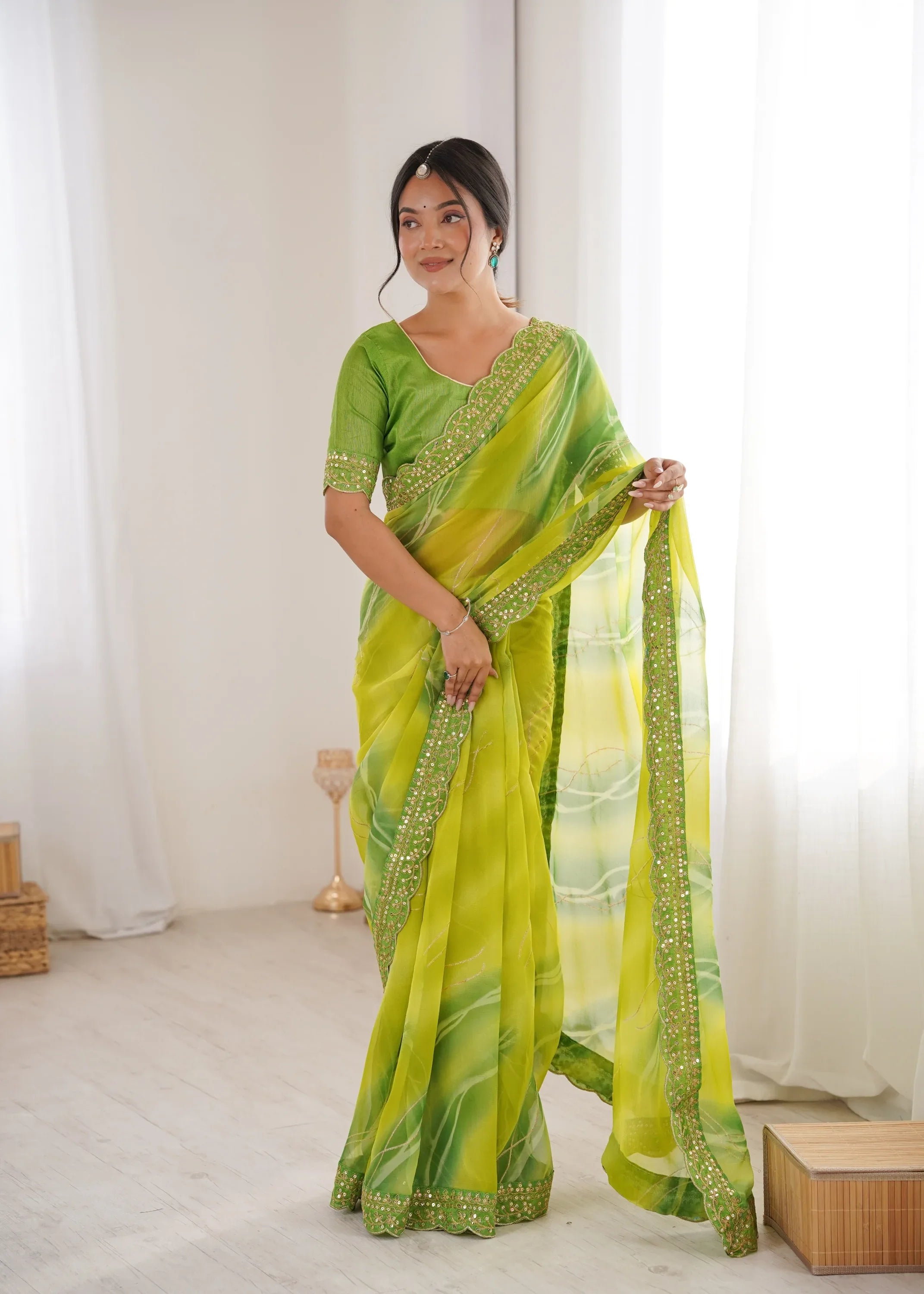Woman wearing a green and yellow saree with a white curtain background Glanzavi
