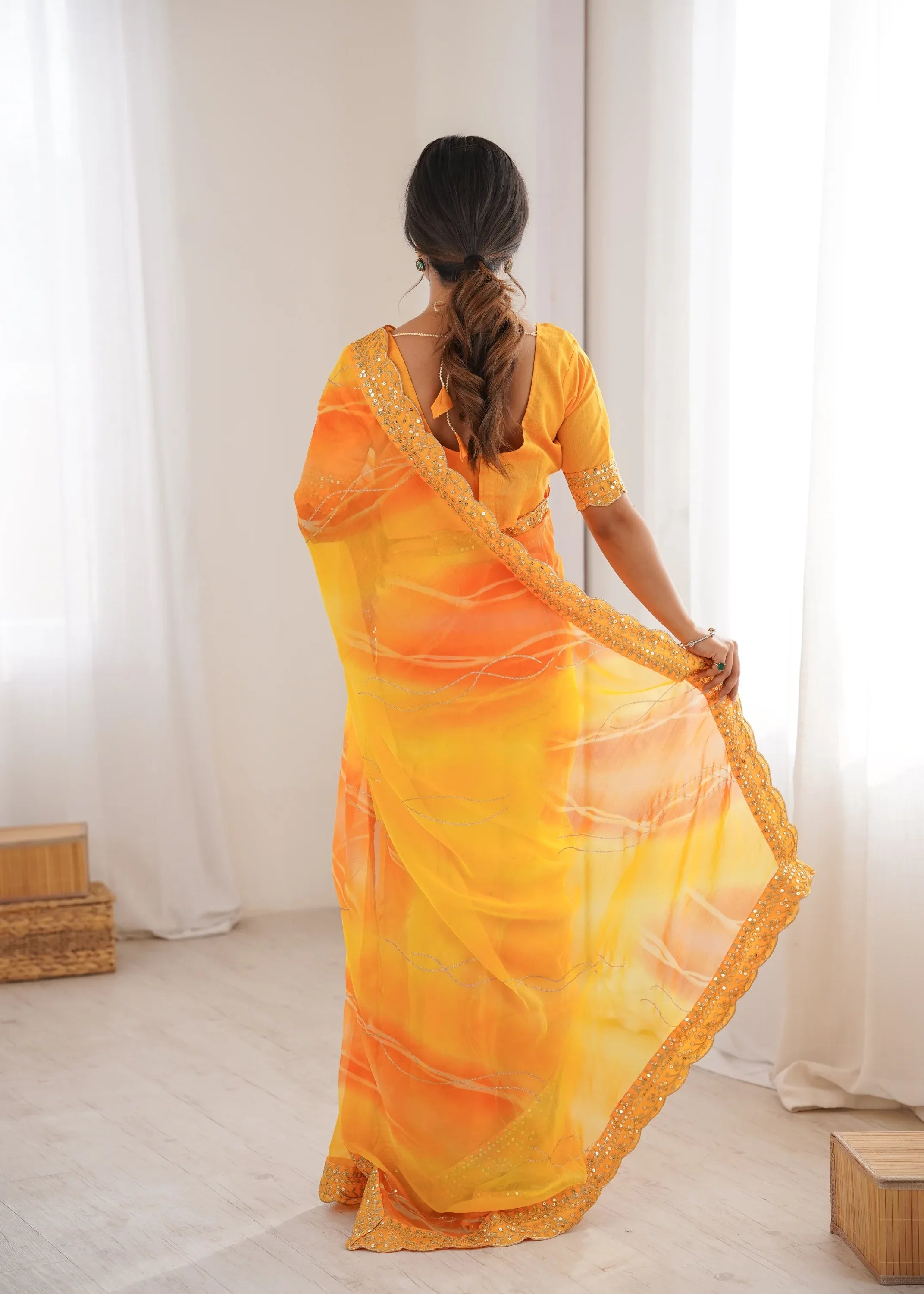 Woman wearing a bright orange saree with a white background Glanzavi