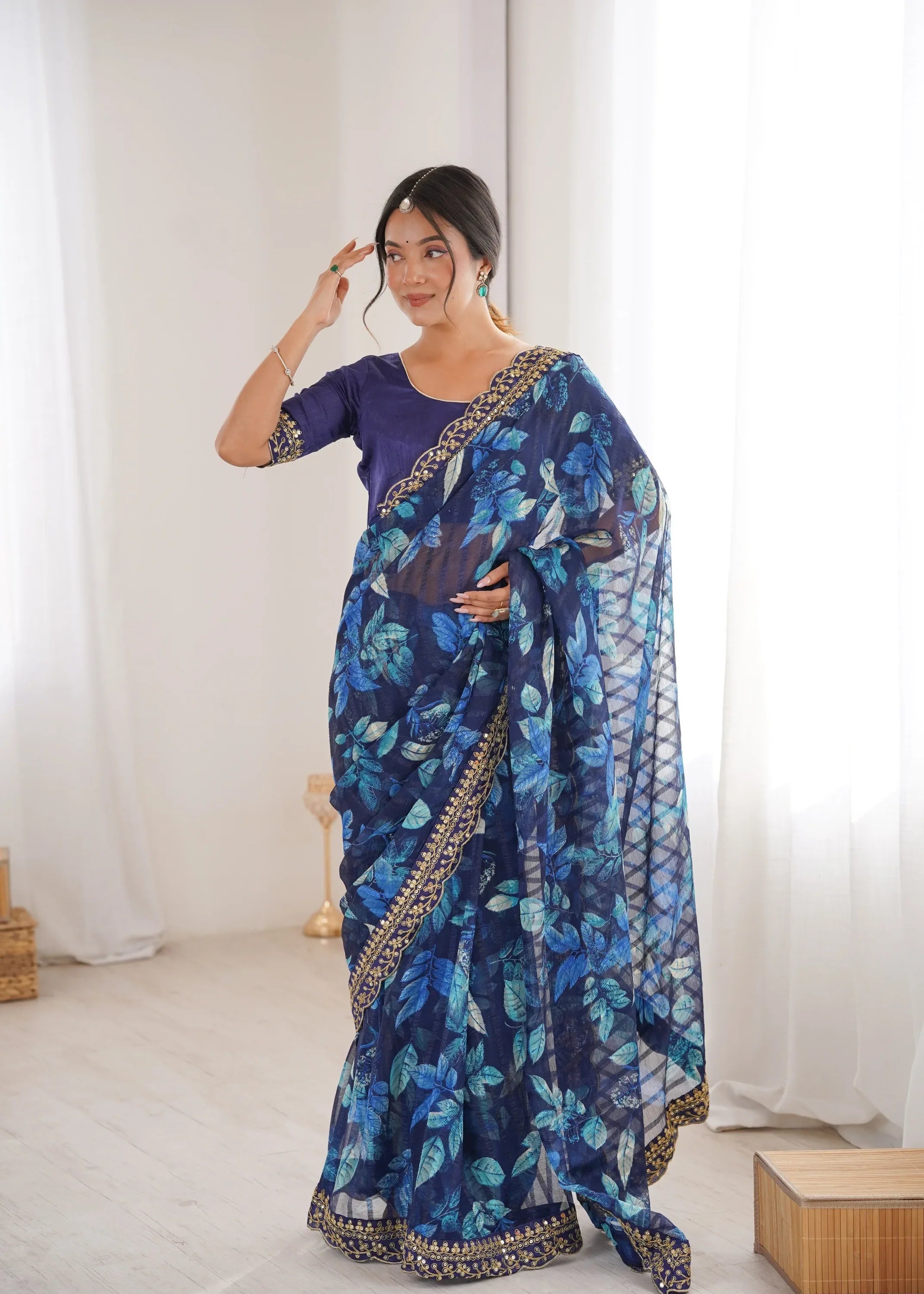 Woman wearing a blue floral saree with a white background Glanzavi