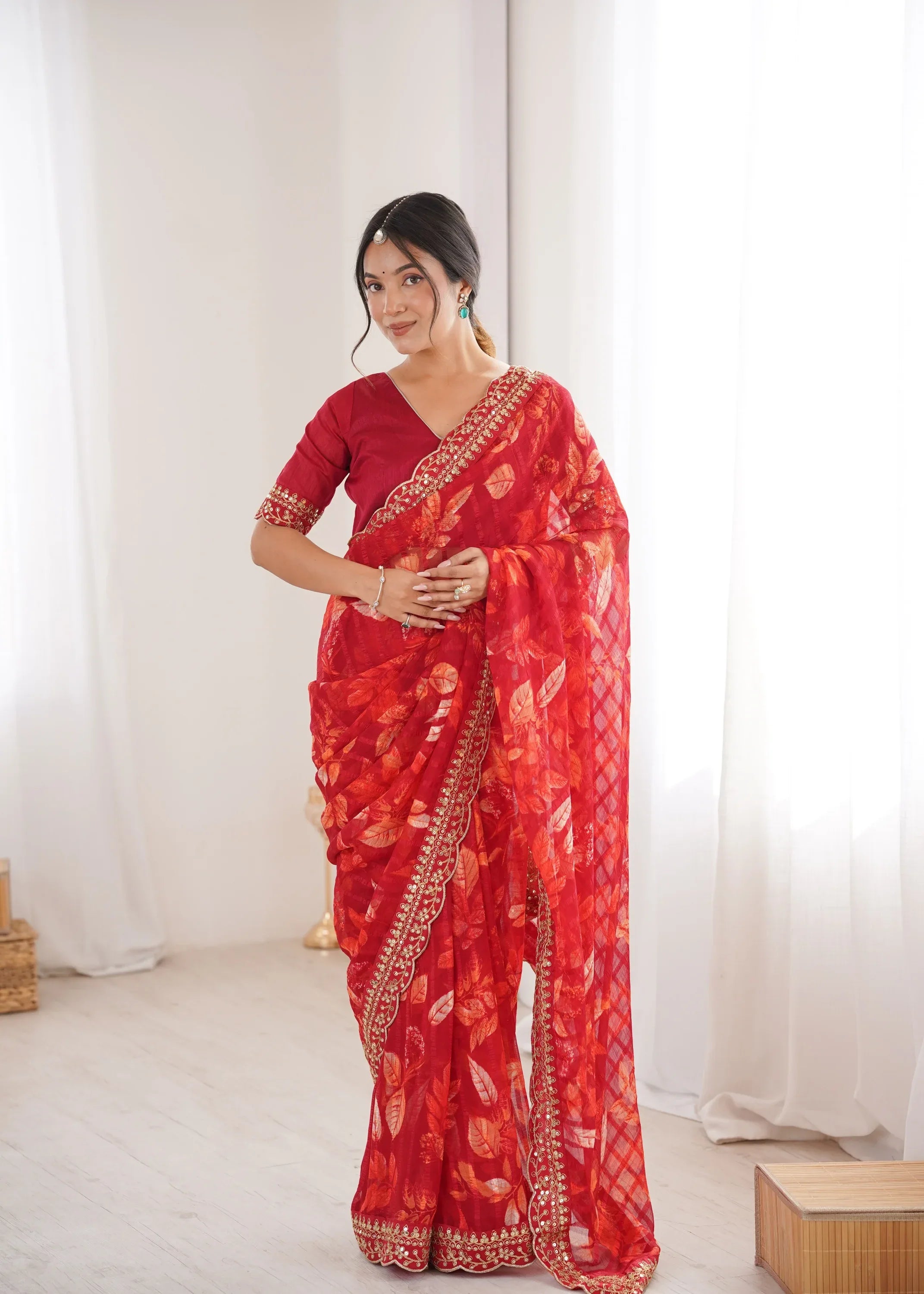 Woman wearing a red saree with white patterns in a minimal indoor setting Glanzavi