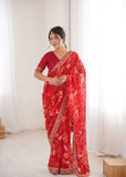 Woman wearing a red saree with white patterns in a minimal indoor setting Glanzavi