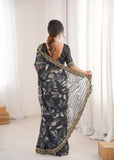 Woman wearing a black floral saree with a white background Glanzavi