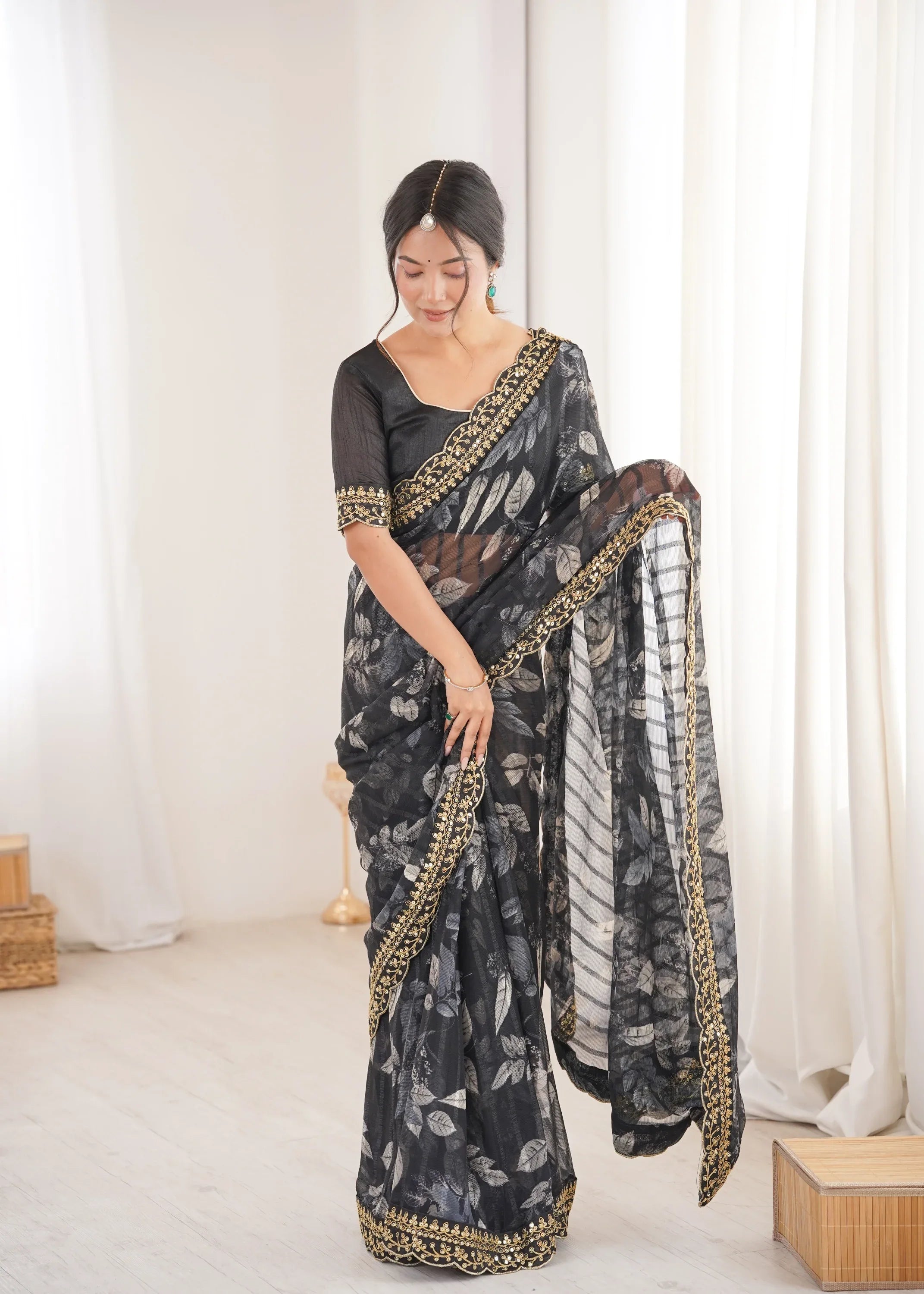 Woman wearing a black floral saree with gold border in a minimalistic setting Glanzavi