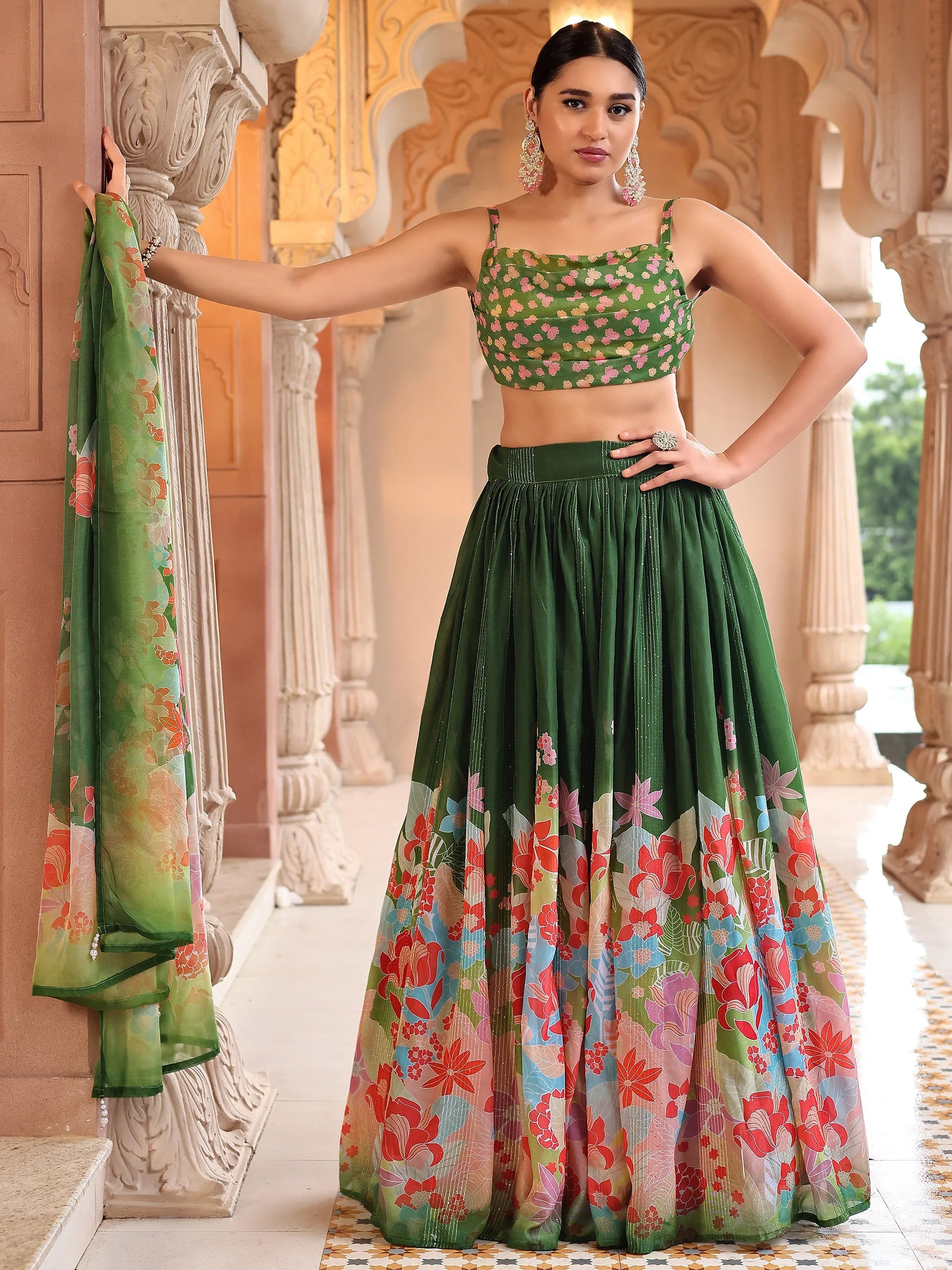 Woman in a green floral outfit standing in an ornate architectural setting Glanzavi