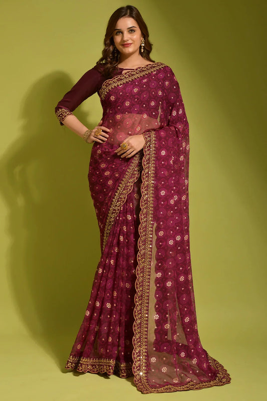 Woman wearing a maroon saree with gold border on a green background Glanzavi