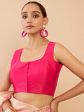 Woman wearing a bright pink top with large hoop earrings on a beige background Glanzavi