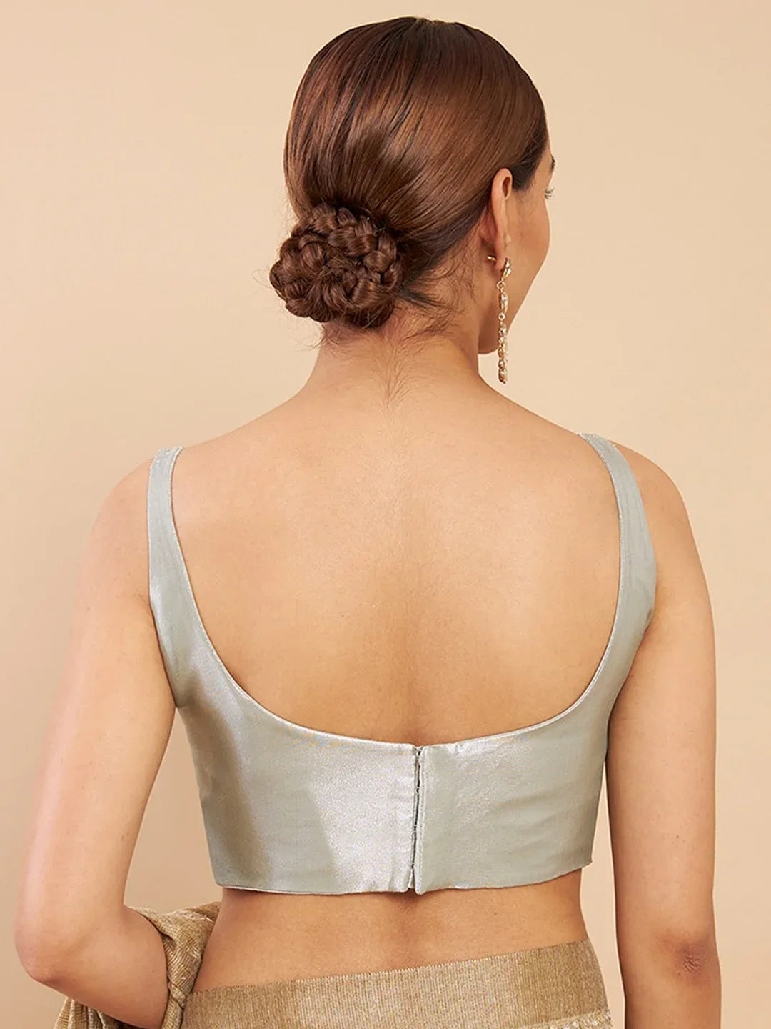 Woman wearing a light green metallic top against a beige background Glanzavi