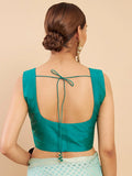 Woman wearing a teal blouse with an open back on a beige background Glanzavi