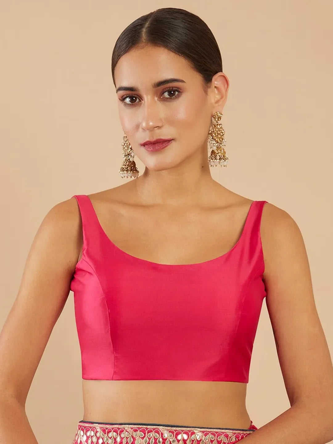 Woman wearing a bright pink top against a beige background Glanzavi