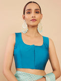 Woman wearing a blue top and green skirt with large earrings on a beige background Glanzavi