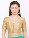 Woman wearing a gold blouse with a plain background Glanzavi