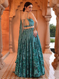 Woman in a teal floral dress standing in an ornate architectural setting Glanzavi