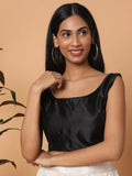 Woman wearing a black top against a beige background Glanzavi