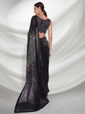 Black saree with sequins on a white draped fabric background Glanzavi