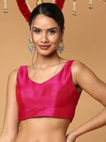 Woman wearing a bright pink blouse with traditional earrings and headpiece on a beige background Glanzavi