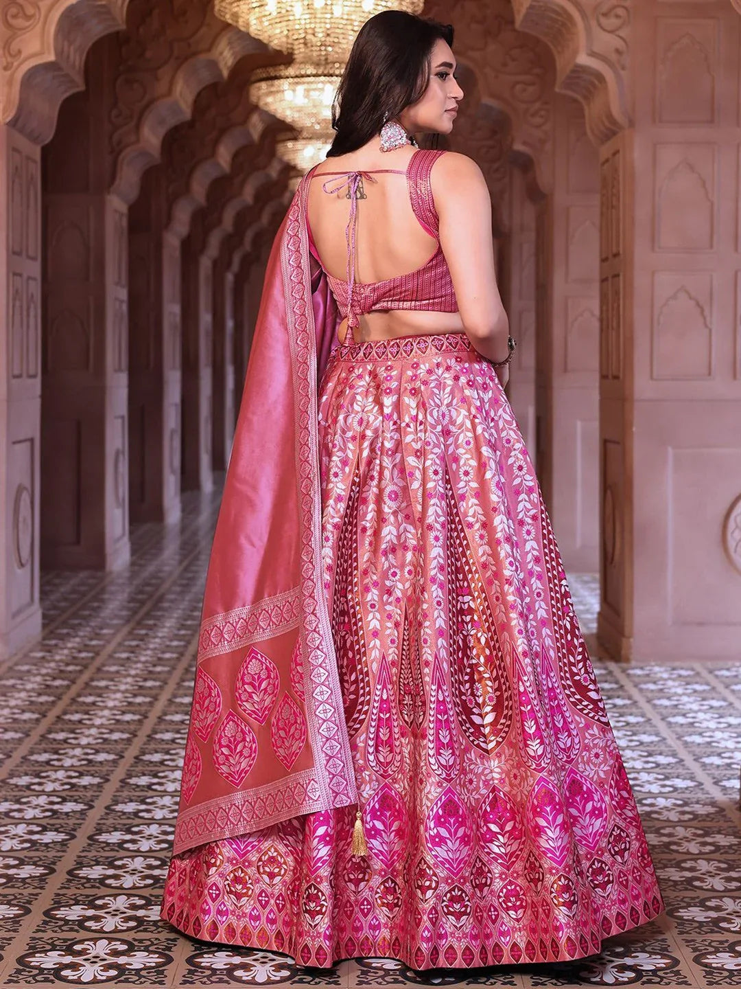 Woman in a pink embroidered traditional outfit standing in an ornate hallway Glanzavi.
