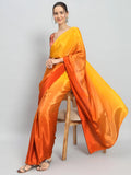 Woman wearing an orange and yellow saree sitting on a chair against a gray background Glanzavi