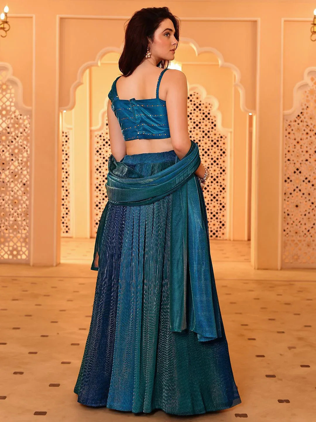 Woman in a blue traditional outfit standing in a decorated room Glanzavi.