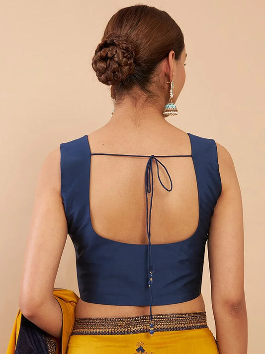 Woman wearing a blue blouse with an open back design on a beige background Glanzavi