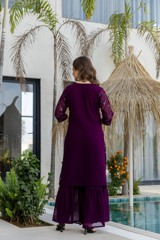 Woman in a purple dress standing by a pool with palm trees in the background Glanzavi