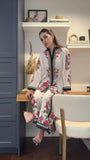 Woman in a floral outfit sitting on a chair in a room with shelves and decor Glanzavi