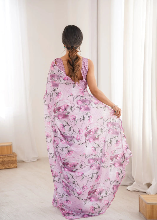 Woman wearing a pink floral dress standing in a bright room with white curtains Glanzavi.