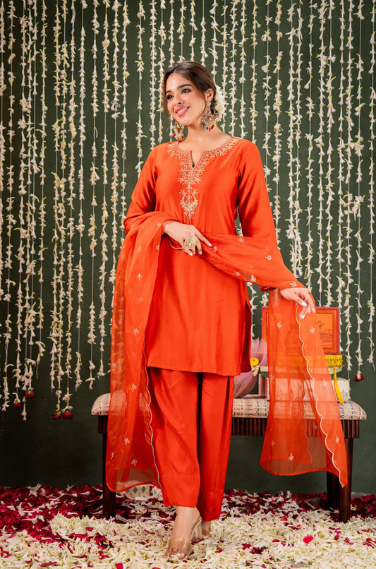 Woman in an orange traditional outfit with a decorative background Glanzavi