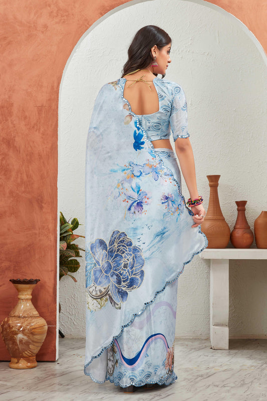 Woman wearing a light blue saree with floral patterns in a room with decorative vases Glanzavi