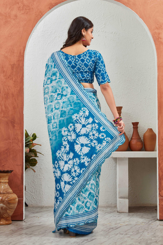 Woman wearing a blue and white saree standing in front of a mirror Glanzavi