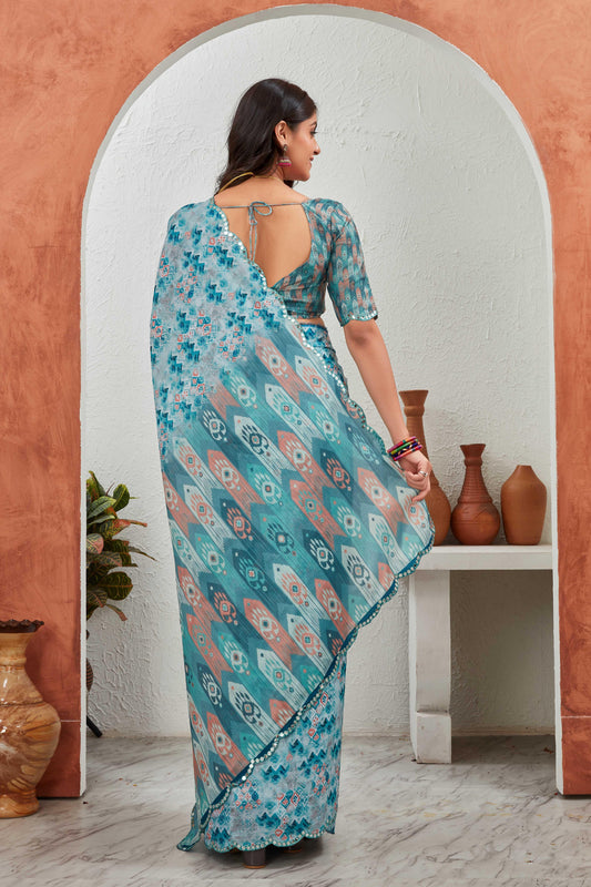 Woman in a floral saree standing in front of a mirror with decorative vases on a shelf Glanzavi