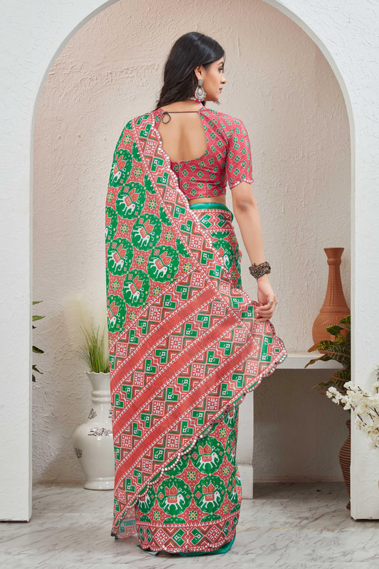 Woman wearing a red and green patterned saree standing in a room with decorative elements Glanzavi