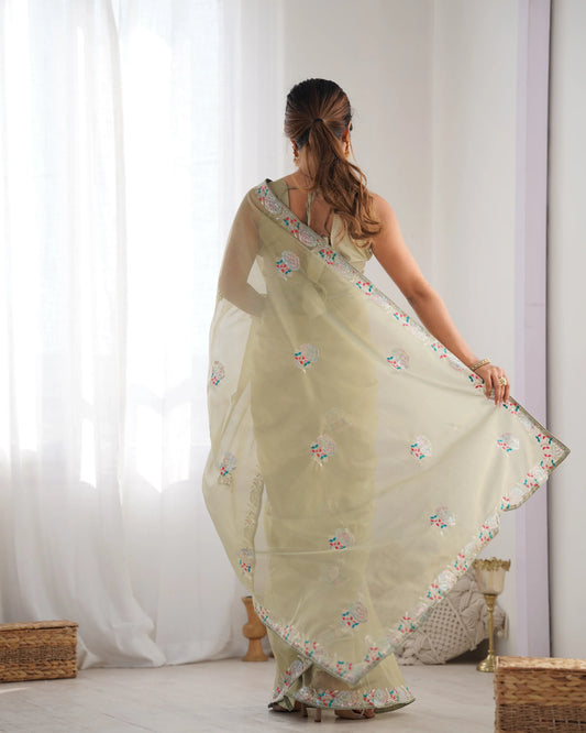 Woman wearing a light green saree with floral patterns in a room with white curtains Glanzavi