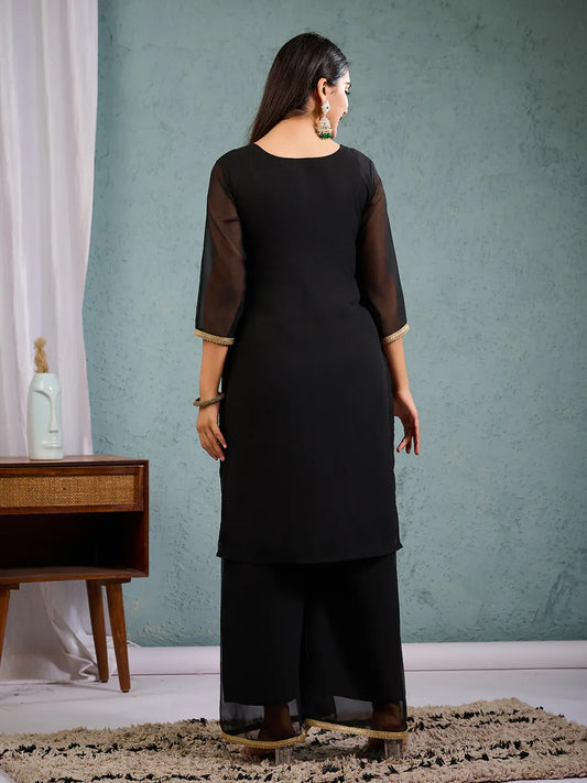 Person wearing a black kurta and black pants in a room with a green wall Glanzavi