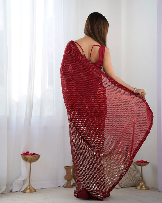 Woman wearing a red saree with a white curtain background Glanzavi
