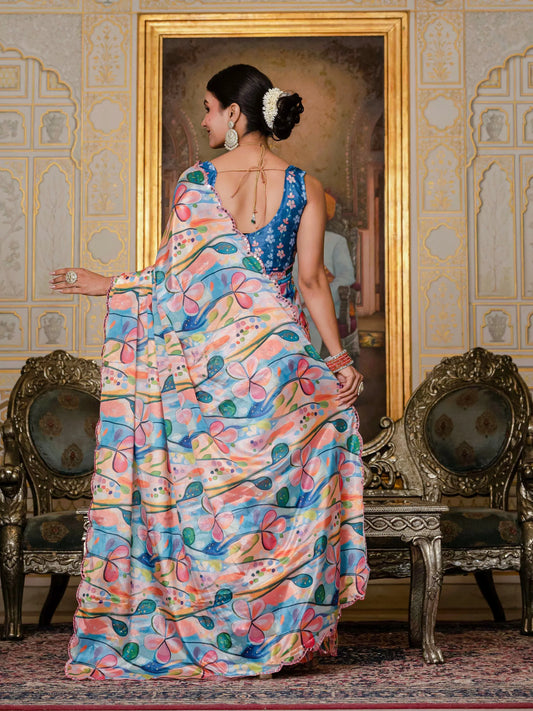 Woman in a colorful saree standing in an ornate room with a painting in the background Glanzavi