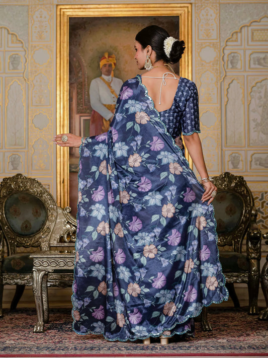 Woman in a blue floral saree standing in an ornate room with decorative walls and furniture Glanzavi.