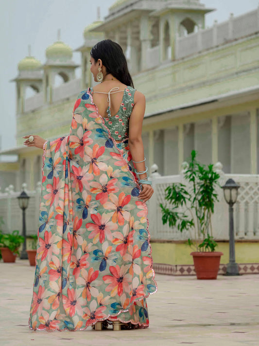 Woman in a floral saree standing in front of a traditional building Glanzavi.
