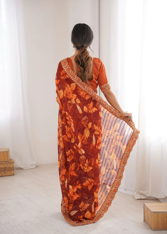 Woman wearing an orange saree with a floral pattern in a minimal indoor setting Glanzavi.