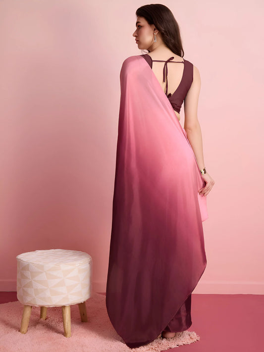 Woman wearing a pink and purple saree with a small stool in the foreground on a pink background Glanzavi