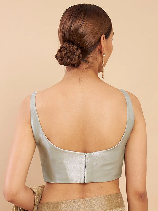 Woman wearing a light green metallic top against a beige background Glanzavi