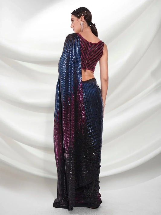 Woman wearing a blue and purple saree with a matching blouse against a white draped fabric background Glanzavi